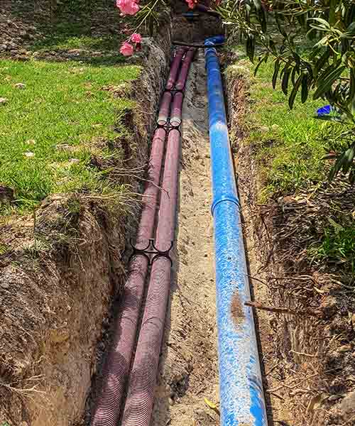 Water lines laying in newly dug trench.